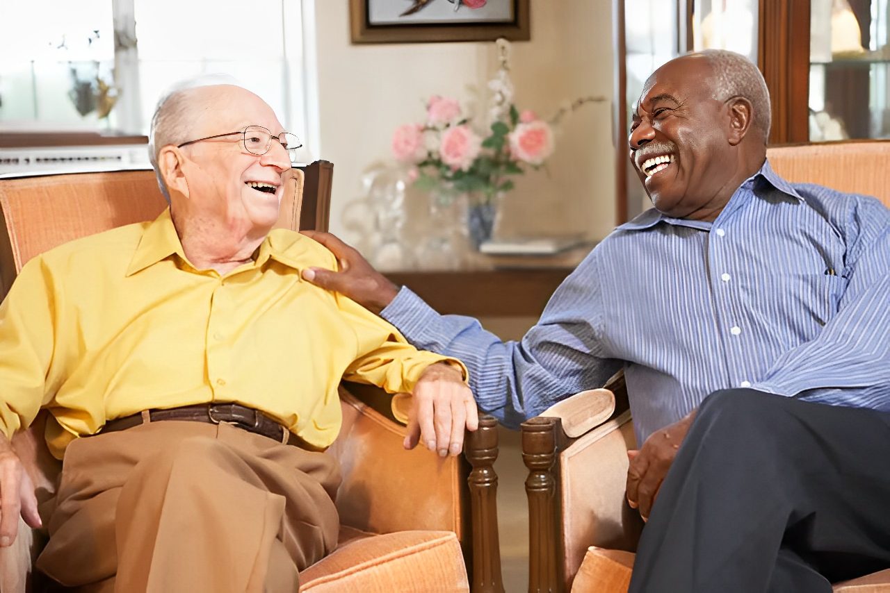 Two elderly men sharing a joyful moment together indoors.