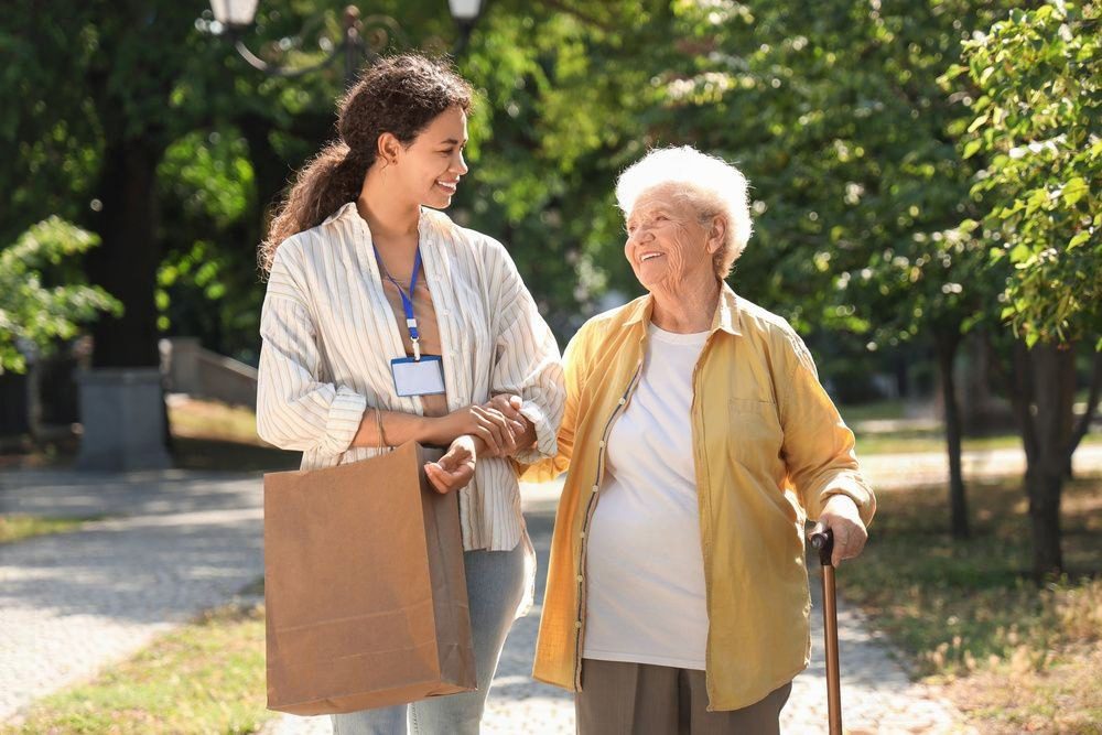 A young woman walks and talks with an elderly woman outdoors.