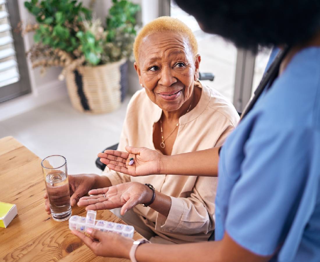 A healthcare worker assists an elderly woman with medication.