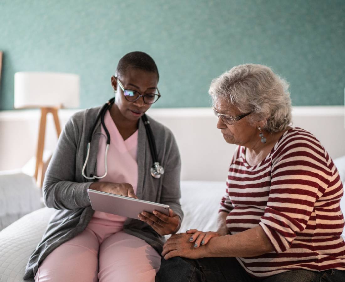 A healthcare professional discusses medical information with an elderly woman.