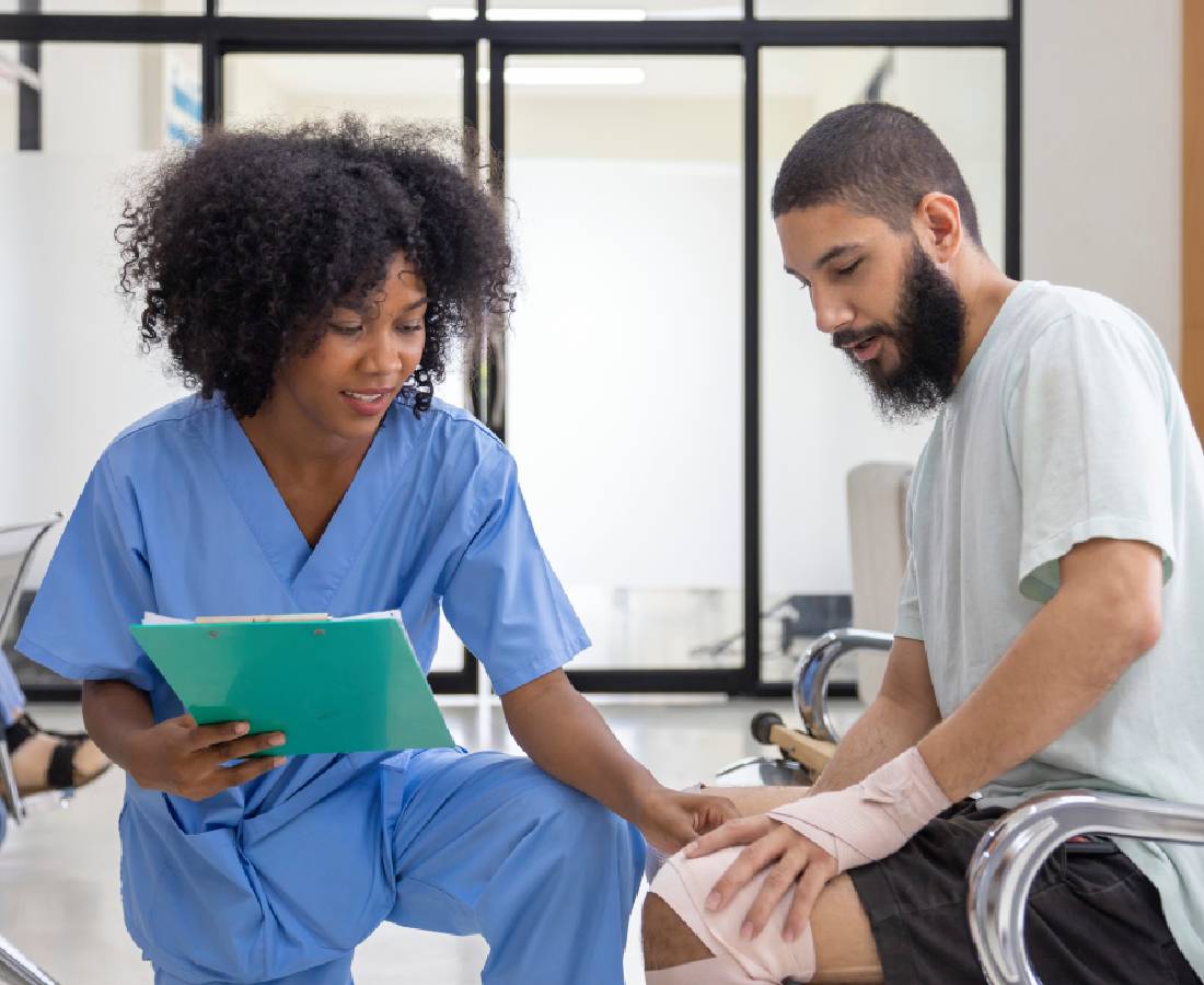 Healthcare professional examining a patient's knee injury in a clinic.