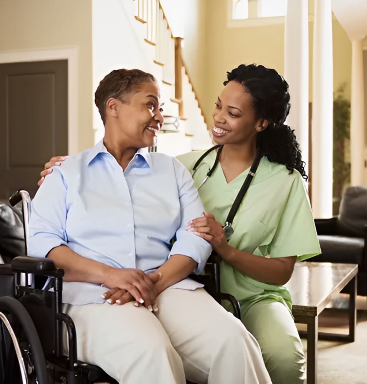 Caregiver assisting a smiling elderly woman in a wheelchair at home.