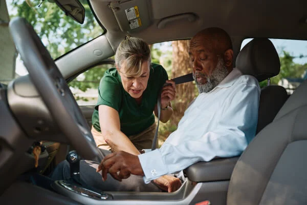 Two men examining the dashboard inside a car.