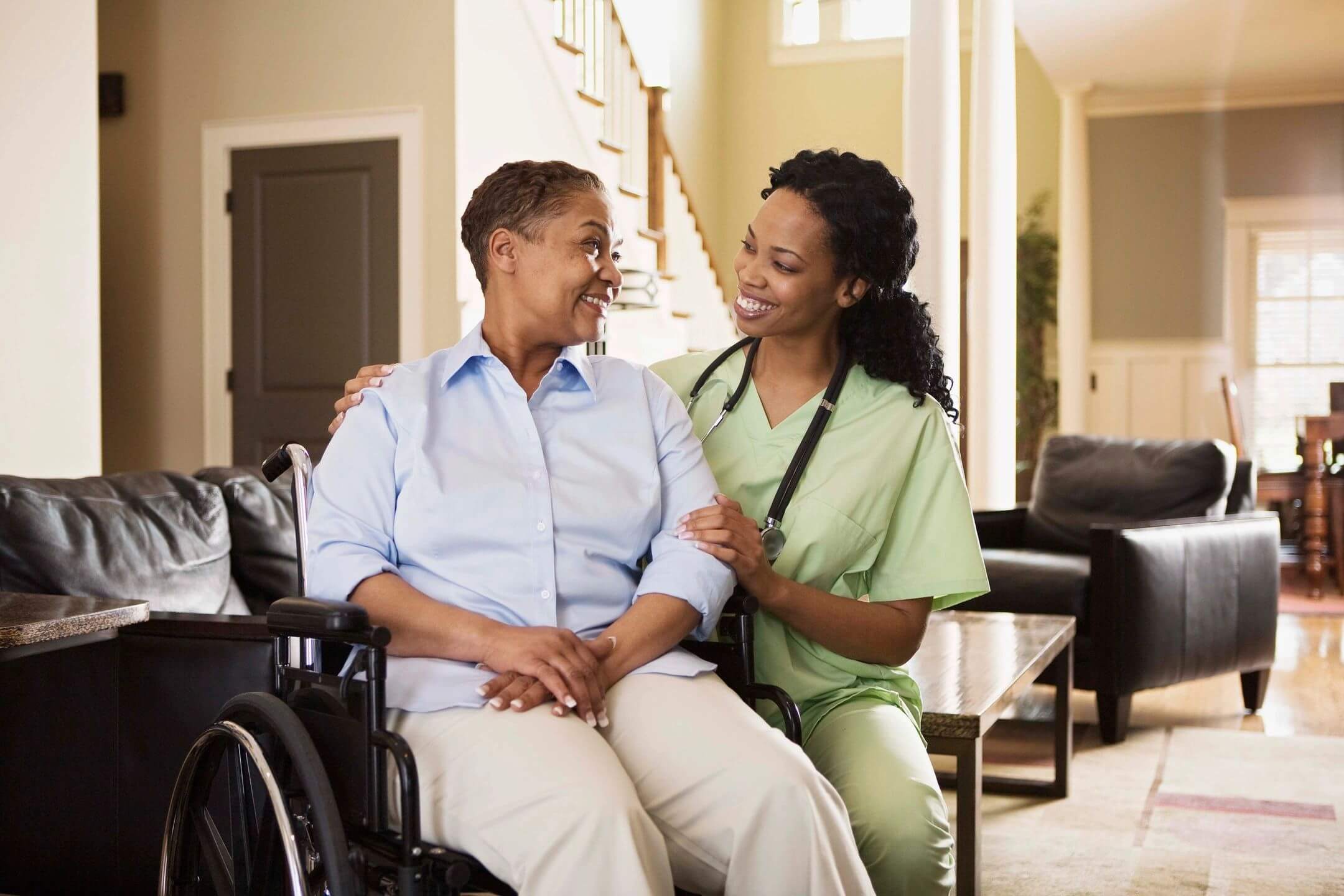 Caregiver assisting an elderly woman in a wheelchair at home.