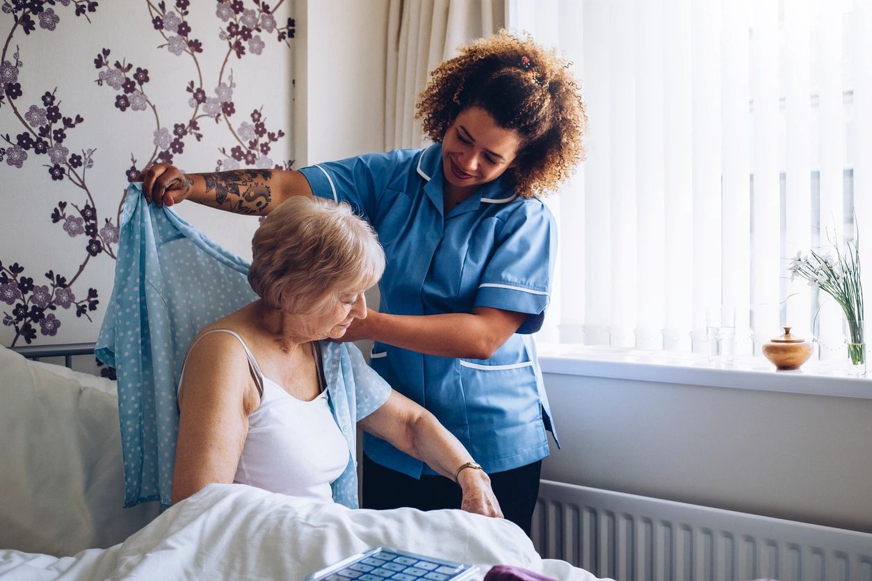 Nurse assisting elderly woman with blood pressure check.