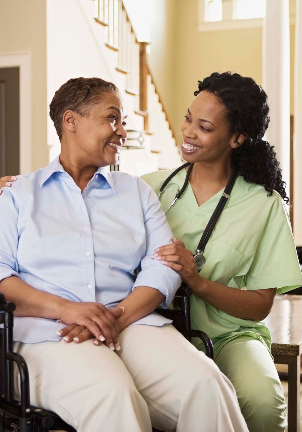 Caregiver assisting an elderly woman in a wheelchair at home.