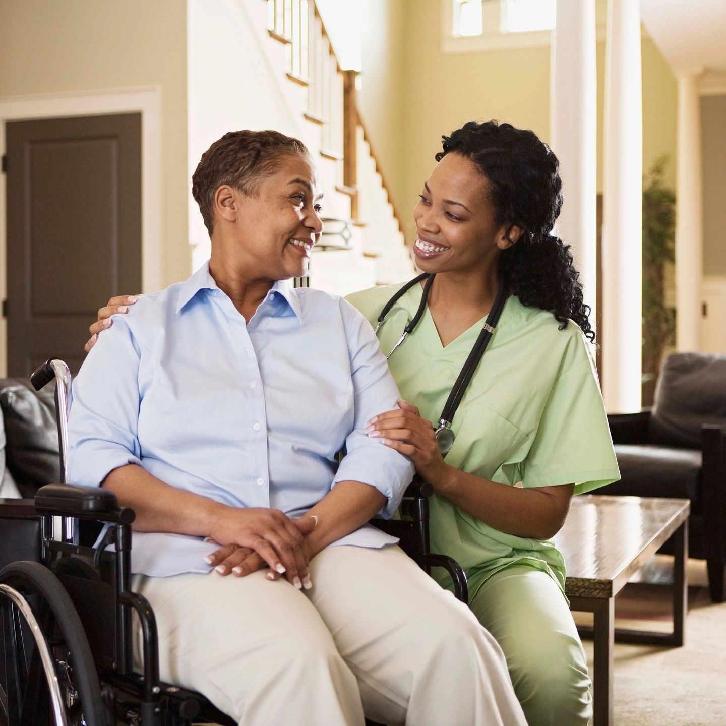 Caregiver assisting an elderly woman in a wheelchair at home.
