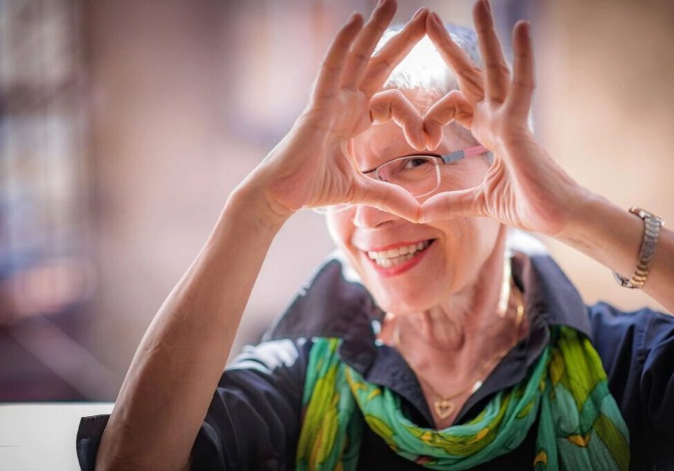 Smiling woman making a heart shape with her hands.